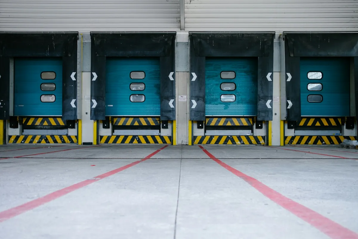 Teal loading dock doors with yellow and black bumpers